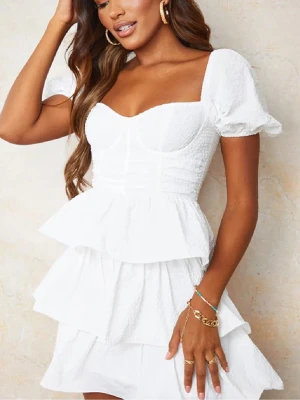 Vit volangklänning - Supersöt vit kortklänning med volanger och perfekt till sommaren! Har använts en gång till urspring. Klänningen är från prettylittlething💕