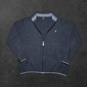 Vintage Ralph Lauren stickad zip up tröja - herr strl M - Säljer en vintage Ralph Lauren stickad zip up-tröja i mörkgrå färg med ljusgrå detaljer i storlek M  👕 Märke: Ralph Lauren 📏 Storlek: M 🎨 Färg: Mörkgrå med ljusgrå detaljer 🧵 Material: 100% bomull 📐 Mått: Längd 68 cm, bredd 55 cm 📍 Skick: Mycket bra skick, delvis noppig (se bilder)  💬 Har du några frågor är det bara att höra av dig! 💰 Vid snabb affär kan priset diskuteras. 📦 Skickar alltid inom 24 timmar!