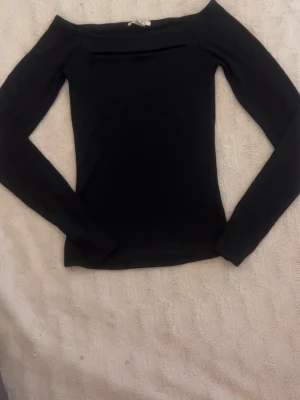 svart offshoulder långärmad topp - snygg svart offshoulder topp med långa ärmar och en öppning. toppens material känns mjukt och stretchigt