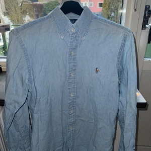 Jeansskjorta från Ralph Lauren - Jeansskjorta från Ralph Lauren i slim fit. Den är i väldigt bra skick, skjortan har alltid hängt på galge så formen är perfekt. 