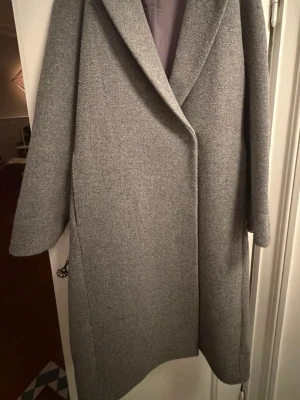 Grå kappa - Grå kappa i storlek XS från H&M Normal i storleken  Bra skick, använd ett fåtal gånger  Slit baktill  2 fickor framtill  Knäpps med tryckknappar  Går att tvätta i maskin 
