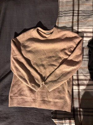 Beige stickad tröja från Invento - Säljer en stilren beige stickad tröja från Invento Italy. Tröjan har rund halsringning, långa ärmar och ribbade muddar vid ärmslut och nederkant. Perfekt för lager på lager och enkel att matcha med olika outfits.