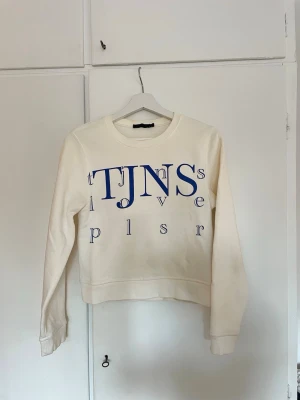 Vit sweatshirt från Tiger of Sweden  - Vit sweatshirt med blått tryck från Tiger of Sweden. Perfekt för en avslappnad och unik/stilren stil. Väldigt mjuk insida och snygg passform.