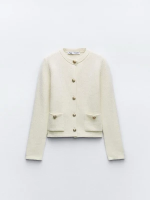 Krämvit kofta från ZARA med guldknappar -  Krämvit kofta från ZARA med rund halsringning och dekorativa guldknappar framtill. Koftan har två fickor framtill och är stickad i ett mjukt material. Perfekt inför våren 💖