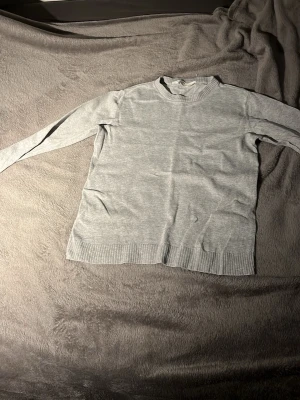 Ljusgrå stickad tröja - En enkel och stilren ljusgrå stickad tröja med rund halsringning och passar 146-152 från H&M. Ny 230kr mitt pris 125kr använd cirka 3 gånger bara. Hör av er vid funderingar?!