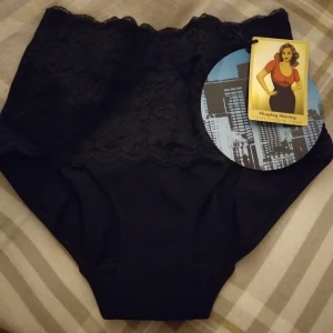 HELT NYA OANVÄNDA Svarta shapingbyxor med spets från Lindex, 36-38. - HELT NYA OANVÄNDA snygga svarta shapingbyxor från Lindex med hög midja och bred spetskant upptill. Modellen heter Goddess Girdle och ger en slät siluett under kläder. Materialet är mjukt och stretchigt med dekorativ spets framtill för extra stil. Strlk 36-38. Felfria.