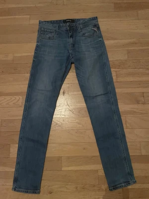 Blå raka jeans från Replay - Säljer ett par klassiska blå jeans från Replay med raka ben och femficksmodell. Jeansen har snygga slitningar och kontrastsömmar som ger en avslappnad look. Perfekta till vardagsstilen och passar till det mesta i garderoben.