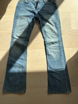 Blå bootcut jeans  - Snygga blå bootcut jeans med klassisk femficksdesign och ljus tvätt. Jeansen har broderade detaljer på bakfickorna 