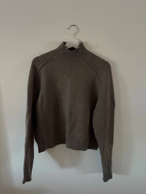 stickad polotröja från H&M - Säljer en brun stickad polotröja från H&M med hög krage och ribbade muddar. Mycket sparsamt använd 