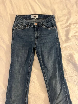 Bootcut  jeans från ONLY - Snygga blå jeans från ONLY med klassisk femficksmodell som är bootcut. Jeansen har normalhög midja och är gjorda i ett mjukt denimtyg med lite stretch för extra komfort. Perfekta till en avslappnad stil. Har gått sönder lite på ett ställe (se bild) går enkelt att sy ihop och inget som syns när man har de på sig. 