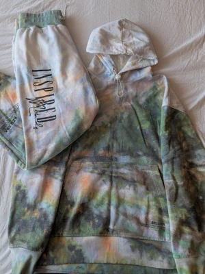 Hoodie & Jogger Set Asos - Size Xs - Comfortable matching hoodie and jogger set in a soft pastel tie dye design. Nature print all over the fabric with printed text details and graphic elements placed across the front, back and on joggers.  Super cozy material, perfect for lounging, casual wear or street style outfits. Hoodie has a front pocket and adjustable drawstring hood while the joggers have an elastic waistband for a comfortable fit.  In good condition in size Xs.  Feel free to message me if you have any questions 🤍 
