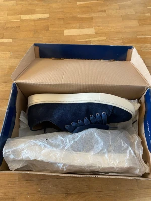 Mörkblåa mockaskor från Polo Ralph Lauren - Snygga mörkblå mockaskor från Polo Ralph Lauren i mocka med vit sula. Klassisk låg modell med rund tå och matchande mörkblå skosnören. Perfekta för dig som gillar stilrena och tidlösa sneakers med premiumkänsla.