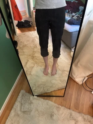 Svarta Capri byxor - Svarta byxor med croppad längd som slutar vid vaden. Byxorna har en rak passform och är perfekta för en avslappnad och trendig stil. Passar bra till både sneakers och sandaler. Perfekta till sommaren i mjukt bomull.