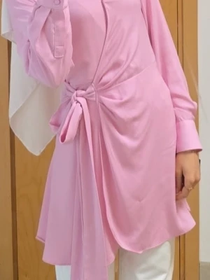 Rosa omlottblus med knytband - Trendig rosa omlottblus med långa ärmar och snyggt knytband i midjan. Blusen har en asymmetrisk nederkant och är tillverkad i ett mjukt, lätt tyg som ger ett fint fall. Perfekt för dig som gillar en feminin och modern stil.