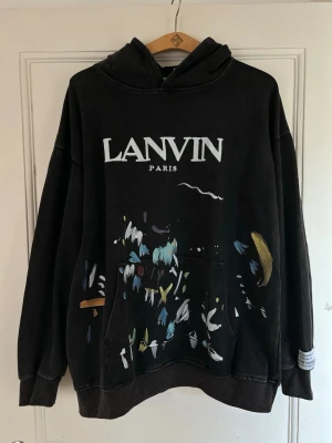 Svart hoodie från Lanvin x gallerydept  - Lägg ett bud! Vill få iväg den.       hoodie från Lanvin Paris med vit logga framtill och  Oversized fit med huva. Perfekt för dig som gillar streetwear och vill sticka ut med en unik design.