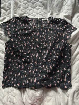 Svart blus med rosa leopardmönster Valerie - Det står att det är storlek 38 men skulle säga att den mer är som en 34. Snygg svart blus från Valerie med rosa leopardmönster och korta ärmar. Blusen har en dragkedja i ryggen och är gjord i ett tunt, transparent tyg med råa kanter. Perfekt för dig som vill sticka ut med en cool och trendig topp.