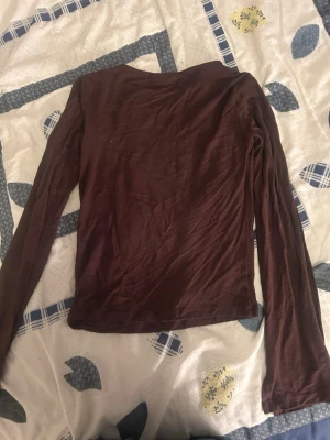 Brun långärmad topp Xoxo by Paris - Mörkbrun långärmad topp från Xoxo by Paris. Enkel och stilren design med rund halsringning och mjukt material som känns skönt mot huden. Perfekt att matcha med jeans eller kjol för en avslappnad look.