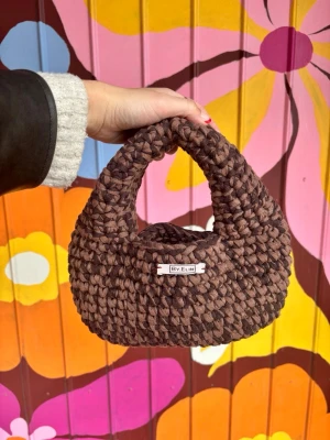 Brun virkad handväska By Elin - Modell ANKI - Mixed brun - Superfin handväska i chunky virkat material från By Elin. Väskan är brunmelerad och har en rundad, mjuk form med kort handtag. Perfekt accessoar för att lyfta din outfit med en unik och trendig touch.
