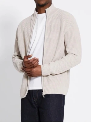 Beige ribbad ziptröja med hög krage - Säljer en stilren beige ribbad ziptröja med hög krage och långa ärmar. Tröjan har dragkedja framtill och är tillverkad i ett mjukt stickat material som ger en clean och modern look. Perfekt att slänga på över en t-shirt för en avslappnad vibe.