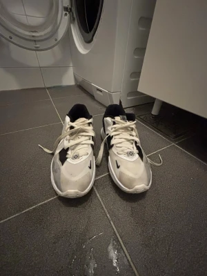 Kyrie Irvine Low 5 - Säljer ett par vita och svarta Nike Kyrie Low 5 sneakers med klassisk swoosh på sidan. Skorna har en sportig design med mesh och syntetmaterial, samt vita snören och svart vadderad häl. Perfekta för dig som gillar streetwear och sportig stil. Funkar att ha på sig vartsom men funkar bäst som basketskor. Skorna har används max i en vecka.