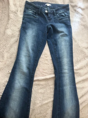 Blå bootcut jeans med slitningar(ordinarie pris:380kr) - Snygga blå bootcut jeans med ljusa slitningar framtill och baktill. Klassisk femficksmodell med knapp och dragkedja. Jeansen har en lätt utsvängd passform och är gjorda i ett mjukt denimtyg som sitter skönt!💕