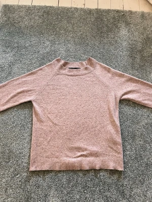 Ljusrosa stickad tröja Vero Moda - Mysig ljusrosa stickad tröja från Vero Moda med rund halsringning.Tröjan har en enkel och stilren design, perfekt att matcha med jeans eller kjol. Materialet känns mjukt och behagligt mot huden. Det finns dessvärre ett litet hål eller ungefär 1 cm längst ner på tröjan för sömmen har gått upp lite. Men det är inget särskilt som man tänker på och är dessutom lätt att fixa.