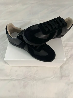 Svarta sneakers i mocka och läder - Snygga svarta sneakers med ovandel i både mocka och läder. Skorna har svarta snören, låg profil och vit insida. Perfekta för dig som gillar stilrena och klassiska sneakers med en modern twist. Skorna är helt oanvända och passar perfekt för nuvarande årstid. 1 :1. Vid fler funderingar är det bara att skriva