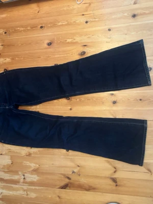 Mörkblå bootcut jeans från Abrand - Säljer ett par mörkblå bootcut jeans med klassisk femficksmodell och låg midja. Jeansen har utsvängda ben och kontrastsömmar. Från Abrand i modellen A 99 low boot. Skulle säga att varan är bra skick. Jeansen är lite urtvättade men inget som syns. Storlek 24.
