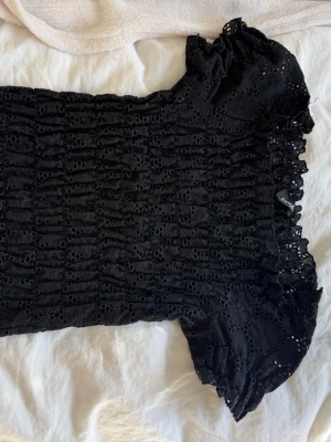 Svart topp från Vegas Paris - Supersöt svart blus från Vegas Paris med broderad spets och puffiga korta ärmar. 