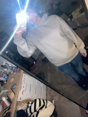 Ljusgrå basic hoodie med huva - En stilren ljusgrå hoodie med huva och magficka. Hoodien har en klassisk passform, ribbade muddar vid ärmslut och nederkant samt en mjuk insida. Perfekt för en avslappnad och trendig look.