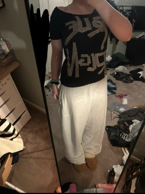 Svart t-shirt med glittrigt tryck - Svart t-shirt med stora glittriga bokstäver i guld på framsidan. T-shirten har korta ärmar och en loose passform, perfekt för dig som gillar statement-plagg och vill ha något som sticker ut. Materialet känns mjukt och bekvämt. Och klippt upp nacken så darför billigare pris
