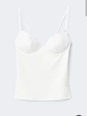 Vit topp från Gina - Stilren vit body med tunna justerbara axelband och formpressade kupor. Materialet ser mjukt och stretchigt ut, perfekt för att ge en smickrande siluett. Enkel och modern design som passar till många olika looks. Har använt den 3 gånger så den är typ som ny