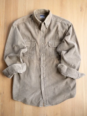 Vintage Beige shirt, size M - Säljer en beige manchesterskjorta i storlek M. Skjortan har klassisk krage, två bröstfickor med lock och knappar framtill. Tillverkad i mjuk manchester som ger en avslappnad och trendig look.