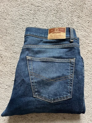 Mörkblå raka jeans Mr. Gordon - Snygga mörkblå jeans från Mr. Gordon med raka ben och klassiska bakfickor. Jeansen har en tidlös tvätt och kontrastsömmar som ger en clean look. Perfekta för dig som gillar enkel och stilren denim.