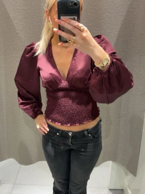 Vinröd med  puffärm - Trendig vinröd topp med puffiga ärmar från Gina 