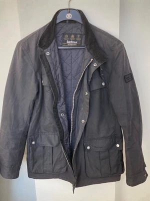 Svart vaxad rock från Barbour - Klassisk svart vaxad jacka från Barbour International med quiltat innerfoder och krage i manchester. Otroligt old money och elegant för vårens kalla utekvällar och även stilig till vardags 