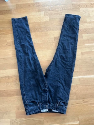 Mörkblå high waist jeans - Säljer ett par mörkblå high waist jeans med raka ben och klassiska fem fickor. Jeansen har en enkel design utan slitningar och är tillverkade i bomullsdenim. Perfekta för en clean och stilren look.
