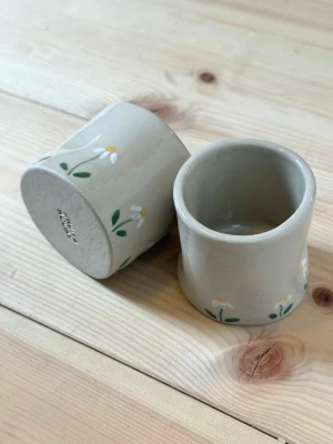Handgjorda keramikmuggar med blommor - Espressomugg i keramik prästkrage – handgjord  Rymmer ca 100 ml.  Två stycken handgjorda espressomuggar i keramik. Perfekt för en god espresso eller som en fin detalj i köket.  Varje mugg är tillverkad för hand, vilket innebär att små variationer och naturliga ojämnheter kan förekomma – det är en del av hantverket och gör varje exemplar helt unikt.  Rekommenderas att handdiskas. Men tål diskmaskin och micro.  Handmade – fruitnclay 