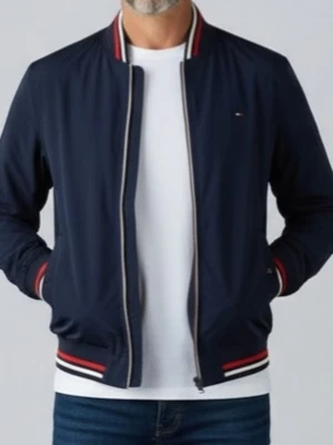 Marinblå bomberjacka Tommy Hilfiger - Snygg marinblå bomberjacka från Tommy Hilfiger med dragkedja framtill. Jackan har ribbade muddar med röda, vita och blå detaljer vid krage, ärmslut och nederkant. Liten logga på bröstet och klassisk sportig look. Perfekt till jeans och t-shirt.