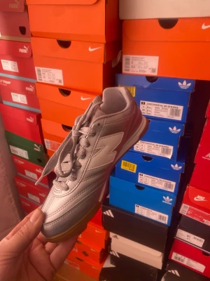 Silvriga New Balance sneakers - Snygga silvriga sneakers från New Balance med klassisk låg profil och gummisula. Skon har en metallic finish, matchande silvriga skosnören och den ikoniska N-loggan på sidan. Perfekt för dig som vill sticka ut med stilrena detaljer.