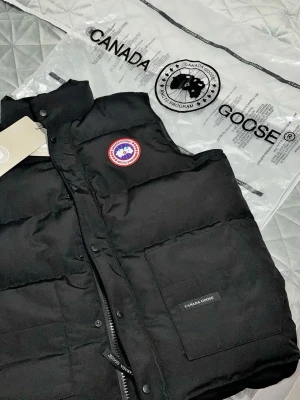 Svart Canada Goose väst  - Snygg svart dunväst från Canada Goose med klassisk logotyp på bröstet. Använts endast ett antal gånger. Storlek: XXL men passar även XL. 