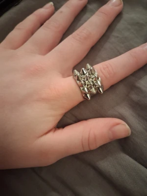 Edblad ring storlek 16:80 - Cool ring i silverfärgad metall med flera små konformade nitar på ovansidan. Ringen har en bred design och ger en edgy, alternativ look. Perfekt för dig som gillar att sticka ut med accessoarerna.