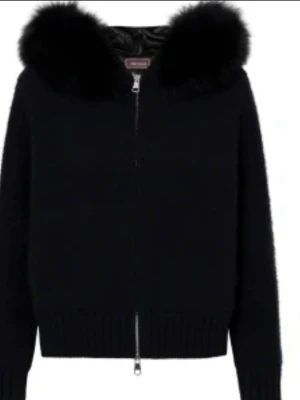 Svart tjock stickad jacka från Alessa - Svart stickad jacka med dragkedja framtill och stor, fluffig fuskpäls runt kragen. Jackan har långärmad design och ribbade muddar vid ärmslut och nederkant. Perfekt för dig som vill ha en mysig och trendig look. Storlek s. Nypris är 2000kr!!!