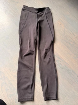Svarta leggings med hög midja - Säljer ett par svarta leggings med hög midja och smickrande sömmar längs benen. De är stretchiga och har en tight passform som sitter snyggt. Perfekta till både oversized tröjor och crop tops. Materialet känns mjukt och följsamt.