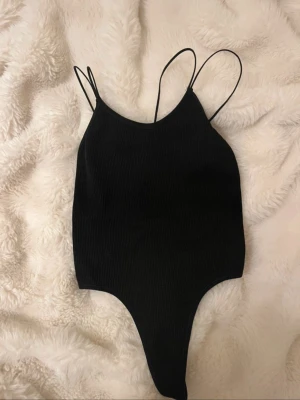 Svart body med tunna band - Snygg svart body från Urban outfitters. Det finns en fin snörning i baksidan. Helt ny med prislapp, storlek S