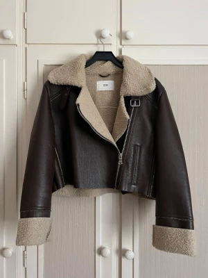 Brun skinnjacka i läderimitation  - Säljer denna jättefina skinnjackan (i läderimitation) då det inte är min stil längre! Sparsamt använd så i fint skick med fluffig insida och dragkedja och spänne och är i midjelängd!