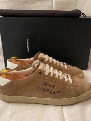 Saint Laurent skor herr  - Säljer ett par beiga Saint Laurent skor i storlek 41| skorna är i bra skick. Nypris: 5000kr mitt pris: 2599kr priset kan diskuteras vid snabb affär. Box och Dustbag medföljer 