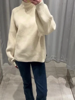 Vit ribbstickad polotröja - Klassisk vit ribbstickad polotröja med hög hals och avslappnad passform. Tröjan har långa ärmar och är tillverkad i ett mjukt, tjockt material som passar perfekt för kyligare dagar. Enkel och stilren design som är lätt att matcha. Storlek Xs i nyskick!