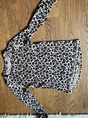 Leopardmönstrad långärmad topp - Snygg långärmad topp med leopardmönster i beige, svart och brunt. Perfekt för dig som vill sticka ut lite extra. Mjuk och stretchig känsla, passar till både jeans och kjol.