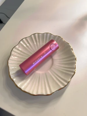 Rosa läppstift från Rituals - Snyggt rosa läppstift från Rituals i en stilren metallhylsa med matt finish. Läppstiftet har en mjuk rosa ton och hylsan är i metall med en elegant design. Perfekt för dig som vill ha en fräsch och feminin look. Pris kan diskuteras, aldrig använt!